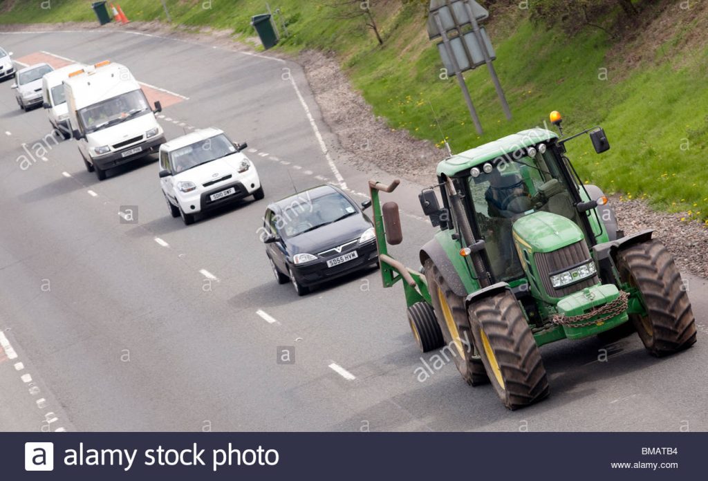 queue-of-traffic-behind-a-slow-moving-vehicle-farming-tractor-on-the-BMATB4